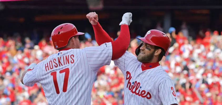 PHILADELPHIA, PA - MARCH 28: Rhys Hoskins #17 and Bryce Harper #3 of the Philadelphia Phillies celebrate Hoskins grand slam in the seventh inning against the Atlanta Braves on Opening Day at Citizens Bank Park on March 28, 2019 in Philadelphia, Pennsylvania