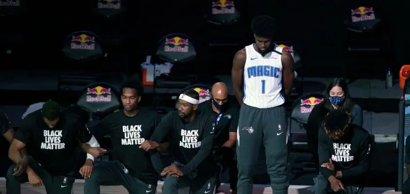 LAKE BUENA VISTA, FL - JULY 31: Jonathan Isaac #1 of the Orlando Magic stands as others kneel before the start of a game between the Brooklyn Nets and the Orlando Magic on July 31, 2020 at The HP Field House at ESPN Wide World Of Sports Complex in Lake Buena Vista, Florida