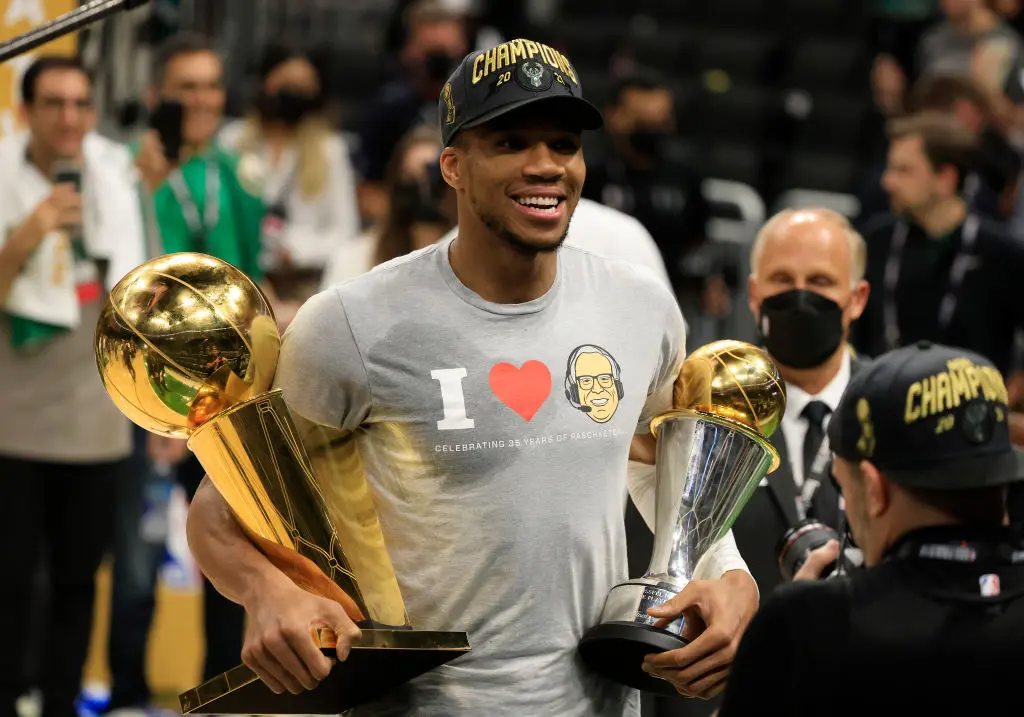 MILWAUKEE, WISCONSIN - JULY 20: Giannis Antetokounmpo #34 of the Milwaukee Bucks holds the Bill Russell NBA Finals MVP Award and the Larry O'Brien Championship Trophy after defeating the Phoenix Suns in Game Six to win the 2021 NBA Finals at Fiserv Forum on July 20, 2021 in Milwaukee, Wisconsin