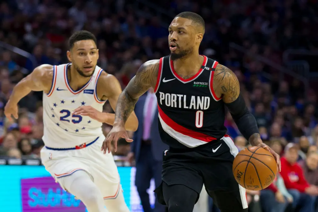 PHILADELPHIA, PA - FEBRUARY 23: Damian Lillard #0 of the Portland Trail Blazers dribbles the ball against Ben Simmons #25 of the Philadelphia 76ers in the first quarter at the Wells Fargo Center on February 23, 2019 in Philadelphia, Pennsylvania