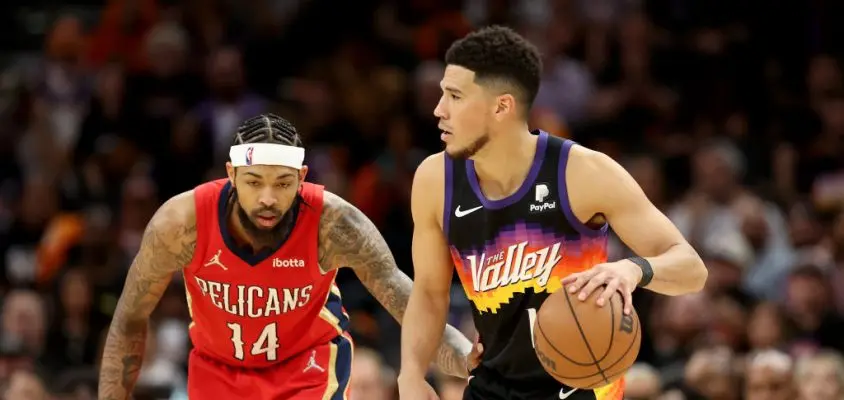 PHOENIX, ARIZONA - APRIL 17: Devin Booker #1 of the Phoenix Suns handles the ball against Brandon Ingram #14 of the New Orleans Pelicans during the second half of Game One of the Western Conference First Round NBA Playoffs at Footprint Center on April 17, 2022 in Phoenix, Arizona. The Suns defeated the Pelicans 110-109.