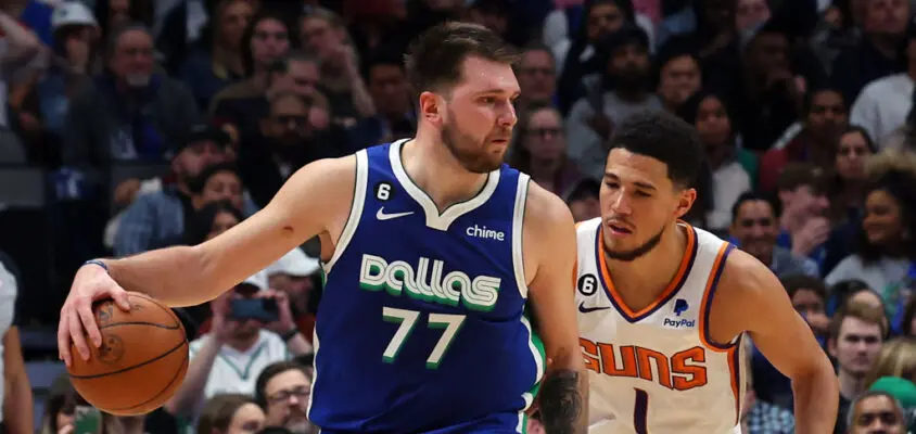 DALLAS, TEXAS - DECEMBER 05: Luka Doncic #77 of the Dallas Mavericks is guarded by Devin Booker #1 of the Phoenix Suns in the second half at American Airlines Center on December 05, 2022 in Dallas, Texas.