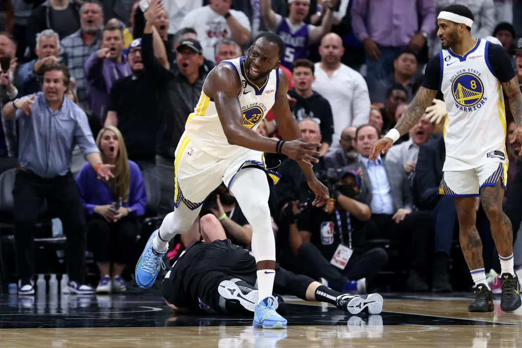 SACRAMENTO, CALIFORNIA - APRIL 17: Draymond Green #23 of the Golden State Warriors steps over Domantas Sabonis #10 of the Sacramento Kings in the second half during Game Two of the Western Conference First Round Playoffs at Golden 1 Center on April 17, 2023 in Sacramento, California. Green was issued a flagrant foul 2 on the play, and ejected from the game.