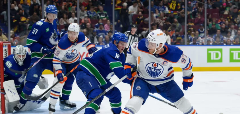 VANCOUVER, CANADA - OCTOBER 11: Sam Lafferty #28 of the Vancouver Canucks defends against Connor McDavid #97 of the Edmonton Oilers during the second period of their NHL game at Rogers Arena on October 11, 2023 in Vancouver, British Columbia, Canada.