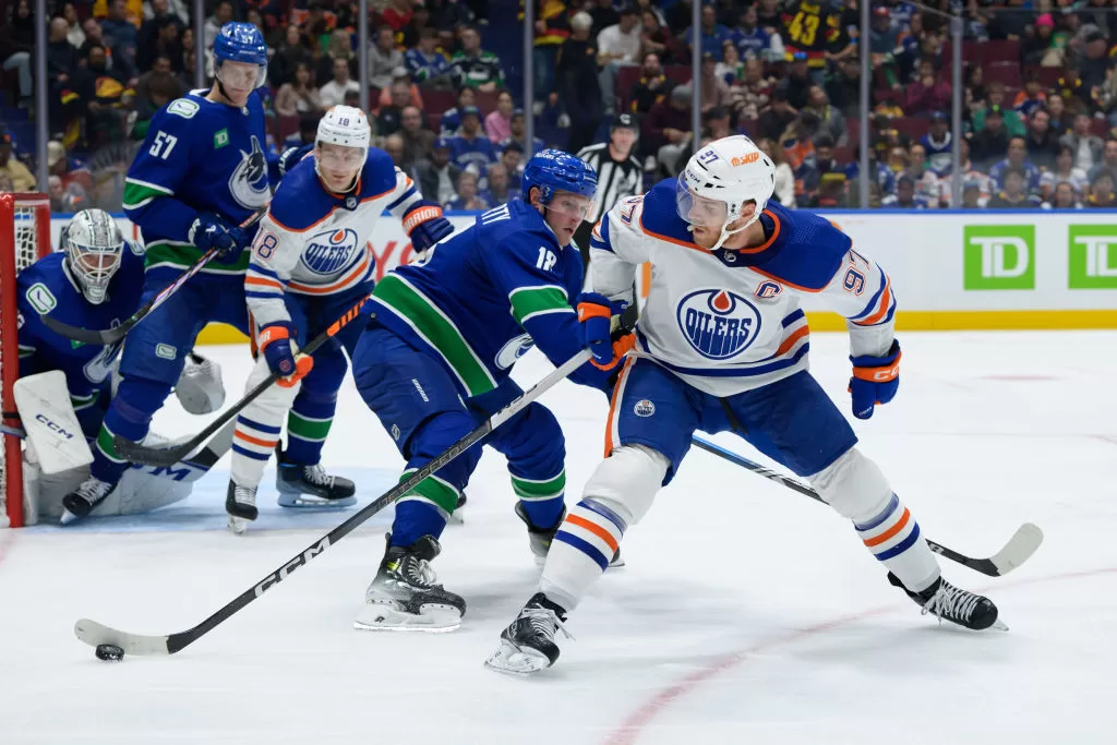 VANCOUVER, CANADA - OCTOBER 11: Sam Lafferty #28 of the Vancouver Canucks defends against Connor McDavid #97 of the Edmonton Oilers during the second period of their NHL game at Rogers Arena on October 11, 2023 in Vancouver, British Columbia, Canada.