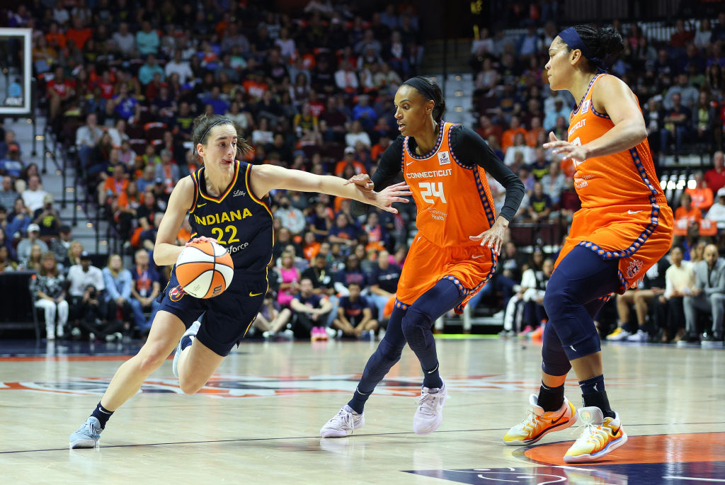 UNCASVILLE, CT - SEPTEMBER 22: Indiana Fever guard Caitlin Clark (22) drives to the basket against Connecticut Sun forward DeWanna Bonner (24) and Connecticut Sun forward Brionna Jones (42) during the First Round and game 1 of the 2024 WNBA playoffs between Indiana Fever and Connecticut Sun on September 22, 2024, at Mohegan Sun Arena in Uncasville, CT.