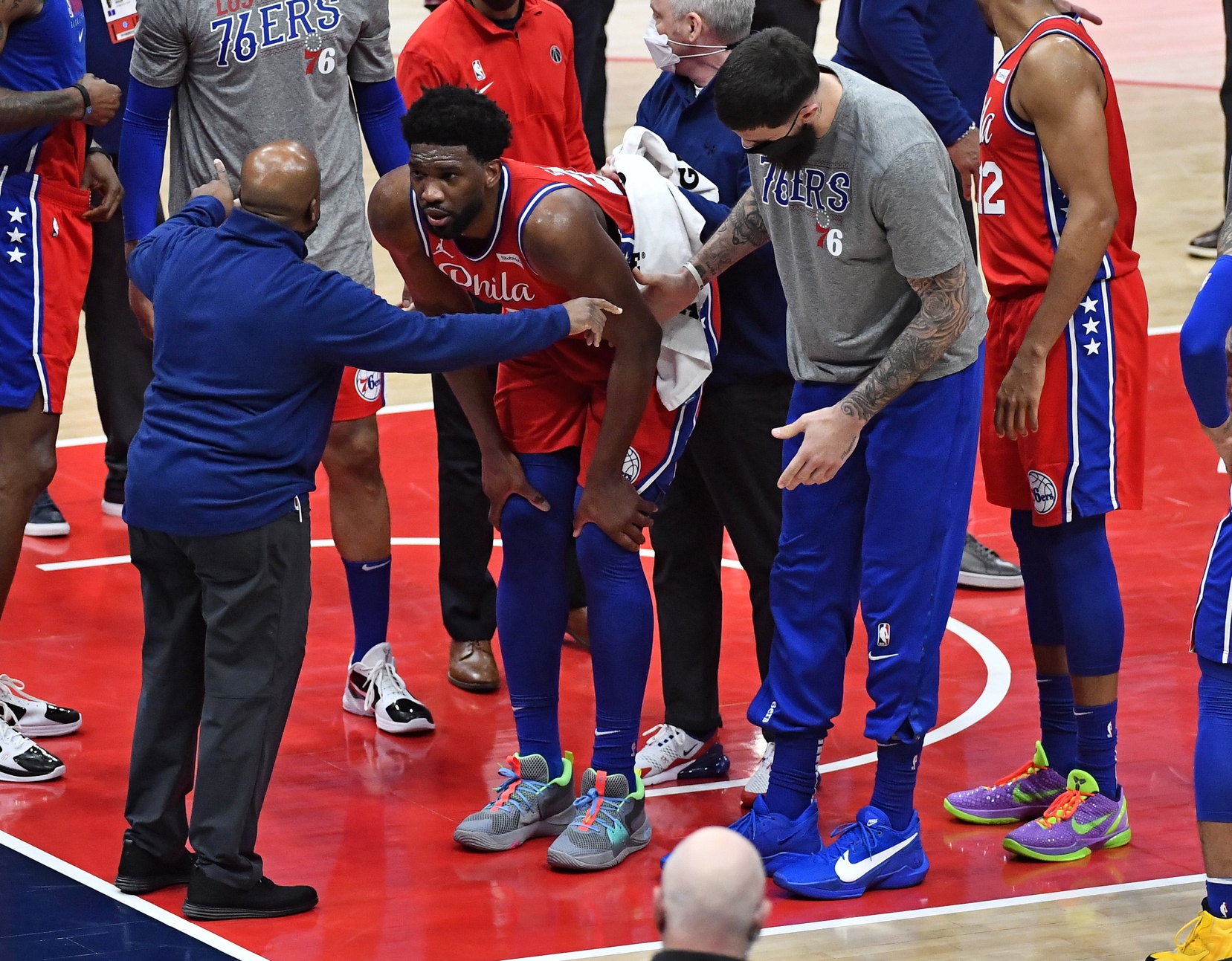 Mar 12, 2021; Washington, District of Columbia, USA; Philadelphia 76ers center Joel Embiid (middle) is examined by a trainer after suffering an apparent leg injury against the Washington Wizards during the third quarter at Capital One Arena. Mandatory Credit: Brad Mills-USA TODAY Sports