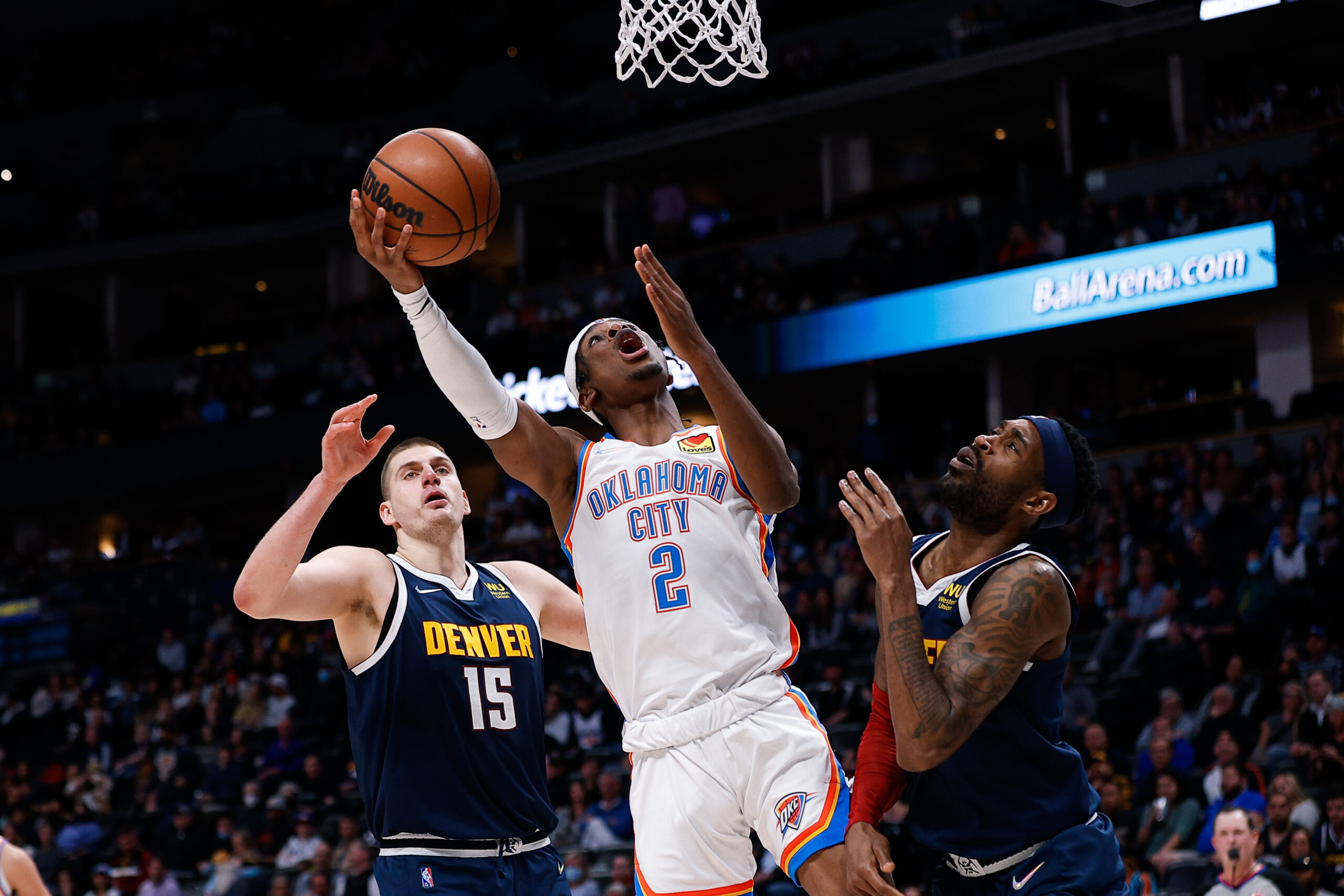 Mar 2, 2022; Denver, Colorado, USA; Oklahoma City Thunder guard Shai Gilgeous-Alexander (2) drives to the net against Denver Nuggets forward Will Barton (5) and center Nikola Jokic (15) in the fourth quarter at Ball Arena.