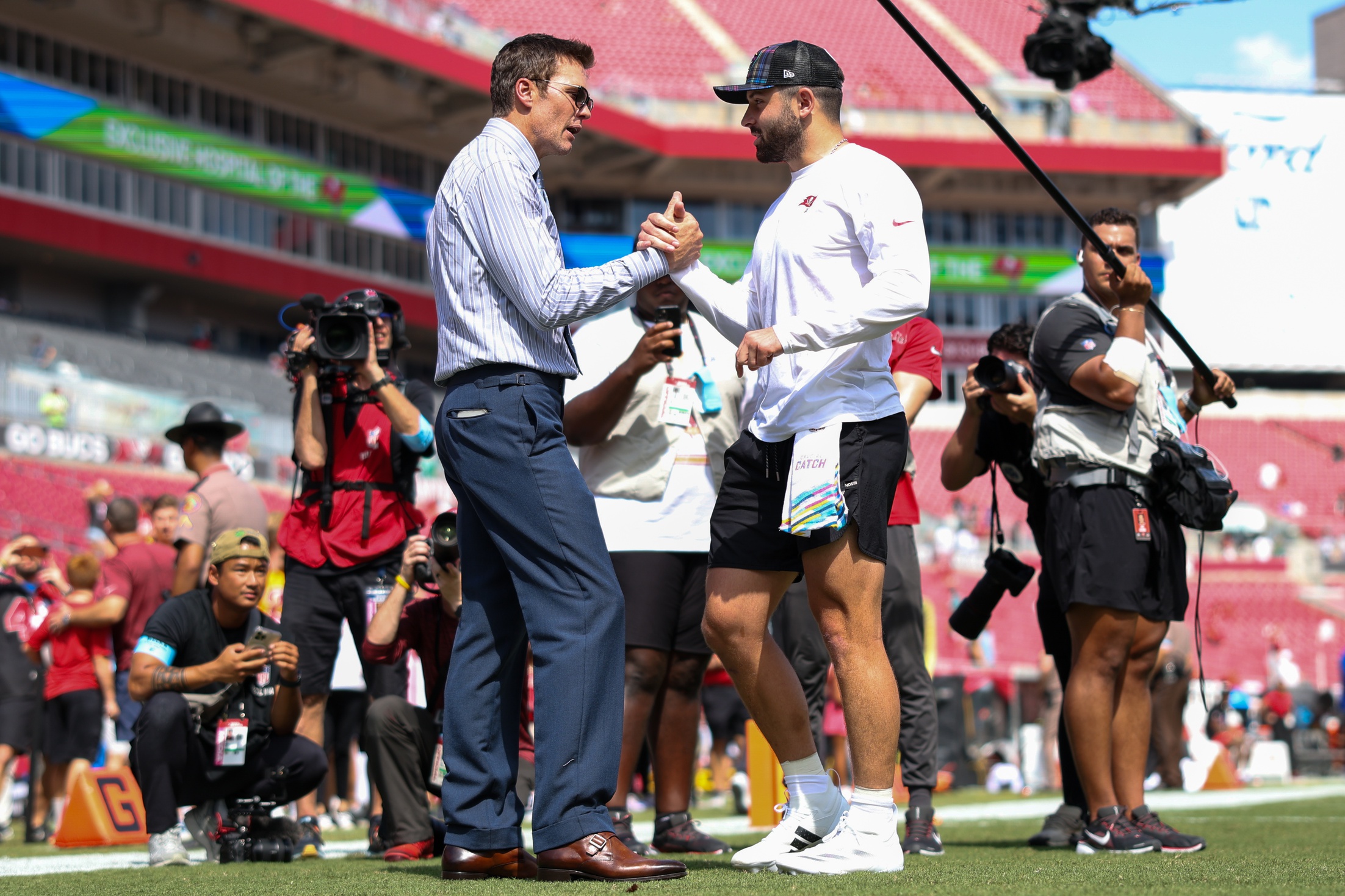 Sep 29, 2024; Tampa, Florida, USA; Fox NFL broadcaster and former NFL quarterback Tom Brady speaks to Tampa Bay Buccaneers quarterback Baker Mayfield (6) before a game against the Philadelphia Eagles at Raymond James Stadium. Mandatory Credit: Nathan Ray Seebeck-Imagn Images