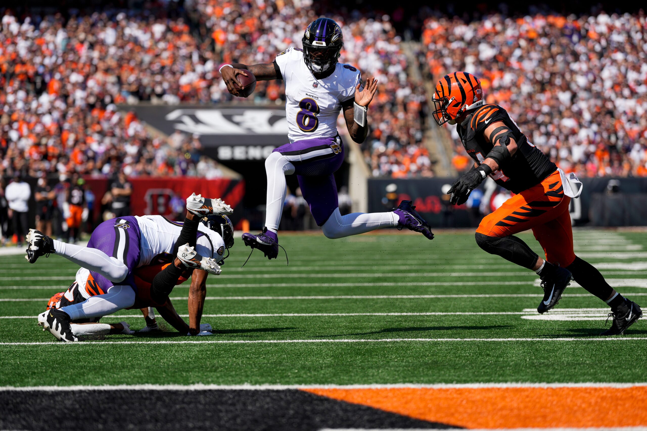 Baltimore Ravens quarterback Lamar Jackson (8) leaps away from Cincinnati Bengals defensive end Sam Hubbard (94) on a keeper in the first quarter of the NFL Week 5 game between the Cincinnati Bengals and Baltimore Ravens at Paycor Stadium in downtown Cincinnati on Sunday, Oct. 6, 2024. The Bengals led 17-14 at halftime.