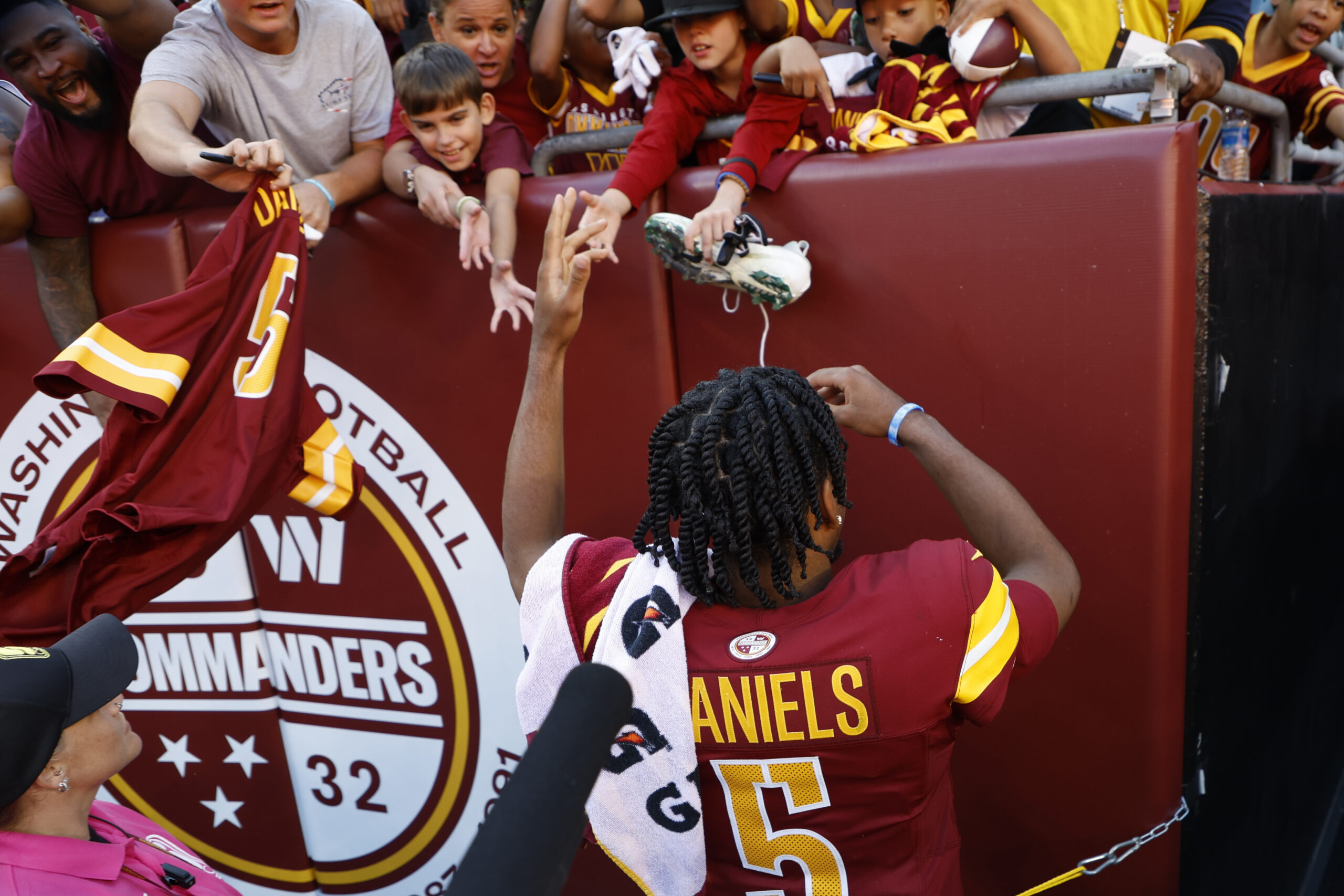 NFL, Oct 6, 2024; Landover, Maryland, USA; Washington Commanders quarterback Jayden Daniels (5) hands pieces of his gear to young fans in the stands while leaving the field after the game against the Cleveland Browns at NorthWest Stadium.