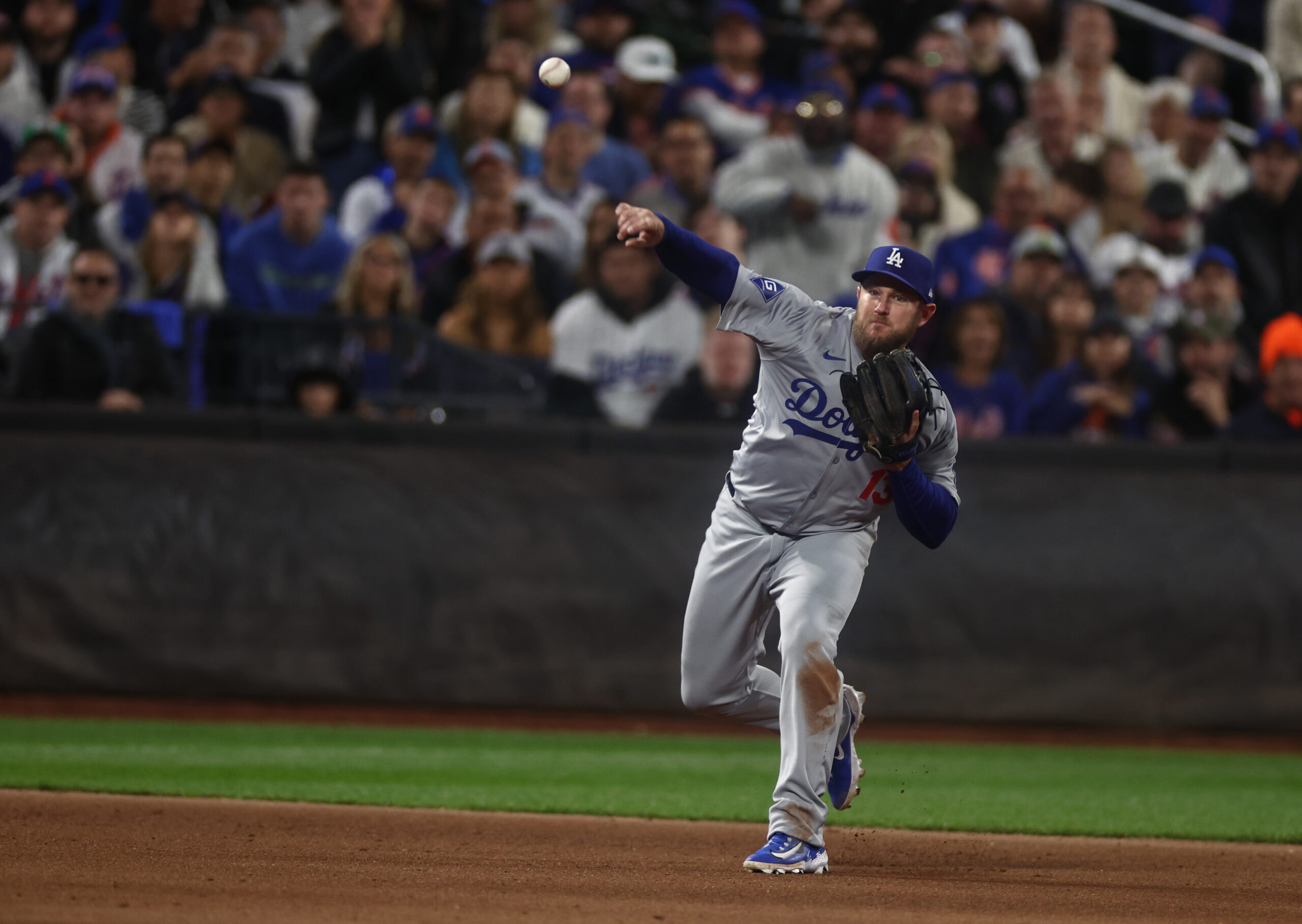 Oct 18, 2024; New York City, New York, USA; Los Angeles Dodgers third baseman Max Muncy (13) throws a ground ball to first base during the fifth inning against the New York Mets during game five of the NLCS for the 2024 MLB playoffs at Citi Field. Mandatory Credit: Vincent Carchietta-Imagn Images