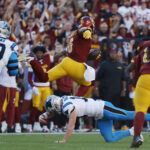 Washington Commanders linebacker Dante Fowler Jr. (6) leaps over Carolina Panthers quarterback Andy Dalton (14) after intercepting a pass en route to a touchdown during the first quarter at Northwest Stadium.