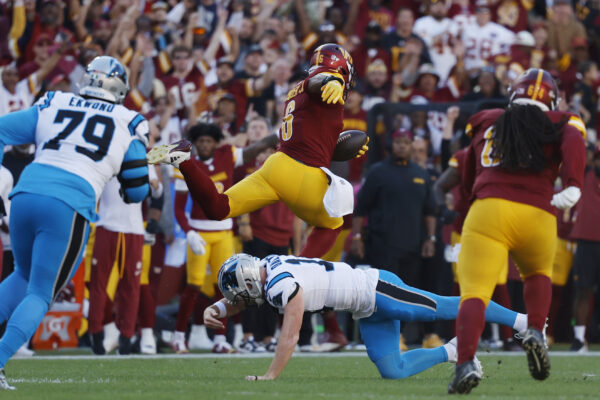 Washington Commanders linebacker Dante Fowler Jr. (6) leaps over Carolina Panthers quarterback Andy Dalton (14) after intercepting a pass en route to a touchdown during the first quarter at Northwest Stadium.