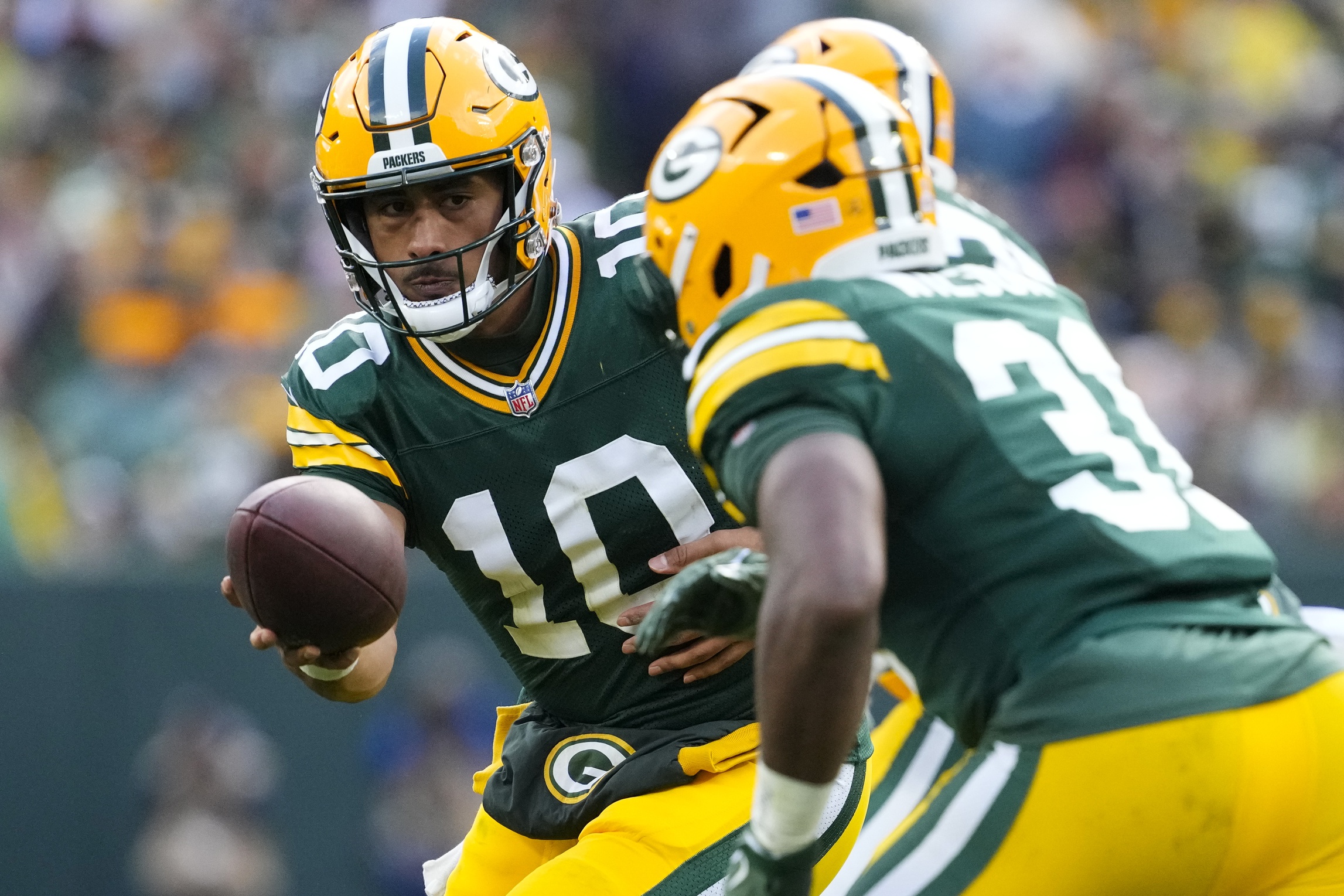 Oct 13, 2024; Green Bay, Wisconsin, USA; Green Bay Packers quarterback Jordan Love (10) hands the football off to running back Emanuel Wilson (31) during the fourth quarter against the Arizona Cardinals at Lambeau Field.