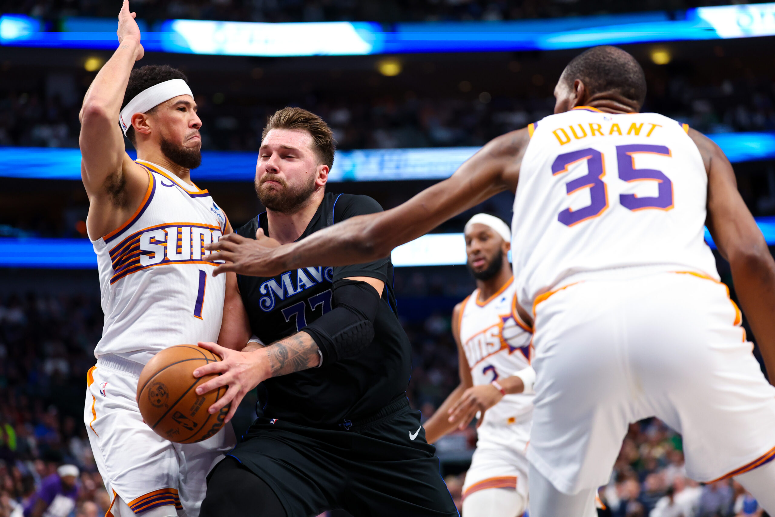 Feb 22, 2024; Dallas, Texas, USA; Dallas Mavericks guard Luka Doncic (77) drives to the basket as Phoenix Suns guard Devin Booker (1) and Phoenix Suns forward Kevin Durant (35) defend during the first quarter at American Airlines Center.