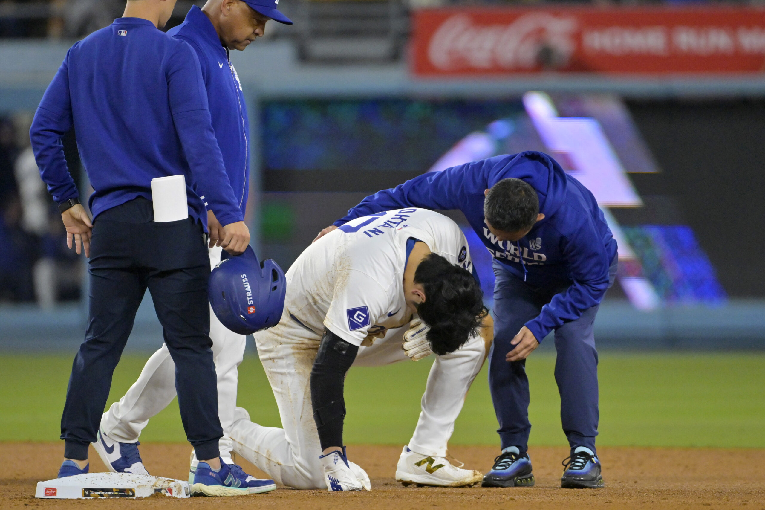 Oct 26, 2024; Los Angeles, California, USA; Los Angeles Dodgers manager Dave Roberts (30) and staff attend to designated hitter Shohei Ohtani (17) at second base after an apparent injury in the seventh inning against the New York Yankees during game two of the 2024 MLB World Series at Dodger Stadium. Mandatory Credit: Jayne Kamin-Oncea-Imagn Images