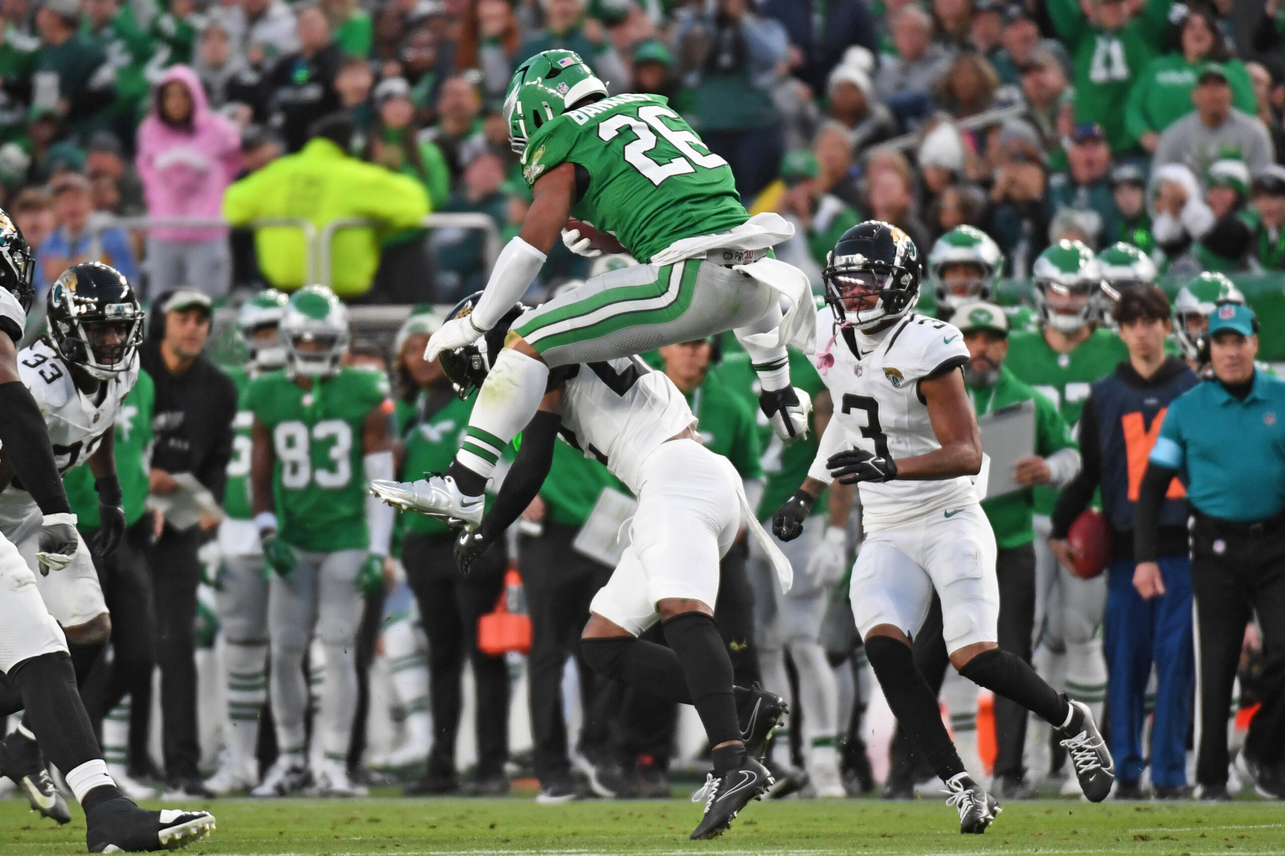 NFL: Jacksonville Jaguars at Philadelphia Eagles. Nov 3, 2024; Philadelphia, Pennsylvania, USA; Philadelphia Eagles running back Saquon Barkley (26) jumps over Jacksonville Jaguars cornerback Jarrian Jones (22) during the second quarter at Lincoln Financial Field. Mandatory Credit: Eric Hartline-Imagn Images