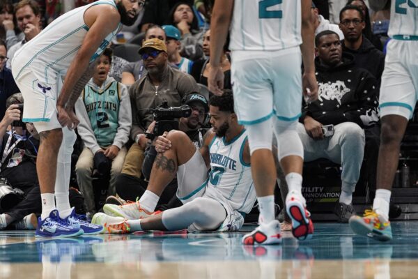 Nov 6, 2024; Charlotte, North Carolina, USA; Charlotte Hornets forward Miles Bridges (0) holds his knee after a collision at the basket against the Detroit Pistons during the second half at Spectrum Center. Mandatory Credit: Jim Dedmon-Imagn Images